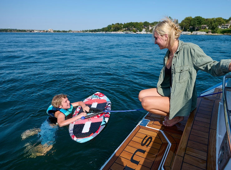 kid in water with board next to boat