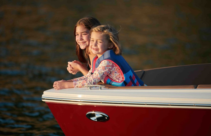 kids sitting at front of boat